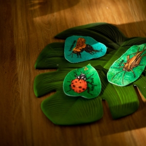 Green felt leaves with ladybug toys for nature-themed sensory play at Innovative Early Learning